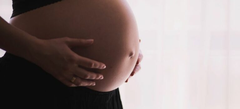 Gravid kvinde tæt på termin med hænderne på maven